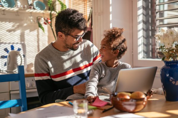 Father and daughter using laptop together at home.